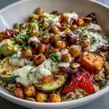 A close-up of a hearty Chickpea Power Bowl reveals sliced avocado, juicy cherry tomatoes, and crunchy pumpkin seeds over warm, spiced chickpeas.