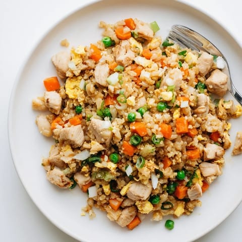 A savory serving of Chicken Fried Rice topped with fresh green onions, ready for chopsticks or a fork.