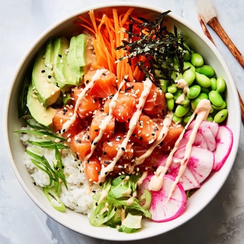 Close-up of a homemade Poke Bowl featuring diced tuna, edamame, and shredded carrots topped with spicy mayo.