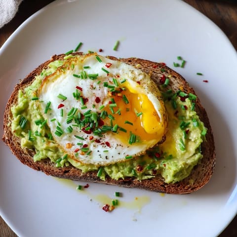 Thick-cut whole-grain toast spread with mashed avocado and lemon, finished with a poached egg and drizzle of olive oil.