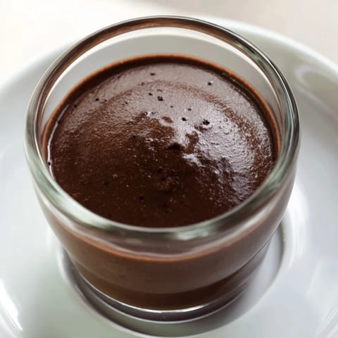 Rich and creamy Chocolate Pudding dessert in a glass, topped with fresh raspberries and a dollop of whipped cream.