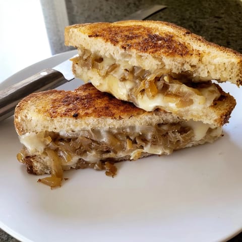 A vegetarian Caramelized Onion Grilled Cheese sits beside creamy tomato soup for a cozy American weeknight dinner.  