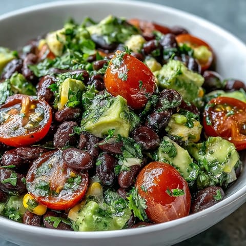 Close-up of the Black Bean and Veggie Bowl with diced avocado, halved cherry tomatoes, and fresh cilantro, drizzled with zesty lime dressing.