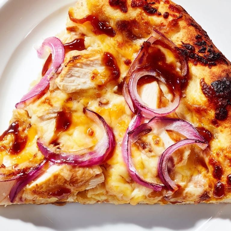 Slice of hot Chicken BBQ Pizza showing tangy barbecue sauce drizzle, tender chicken pieces, and fresh cilantro garnish. 