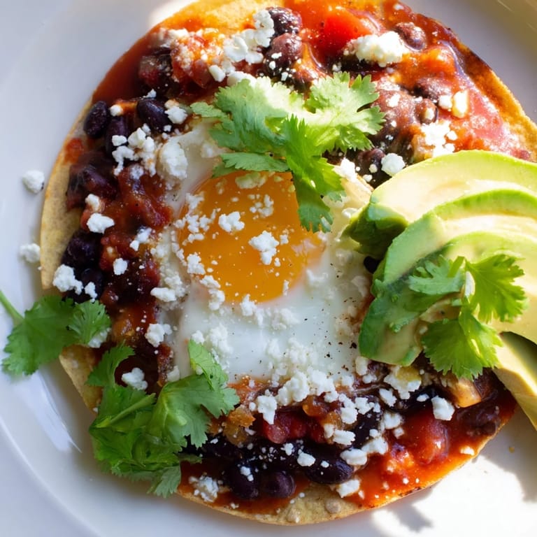 Crisp corn tortillas hold fried eggs for this easy Huevos Rancheros recipe, topped with fresh cilantro and avocado.