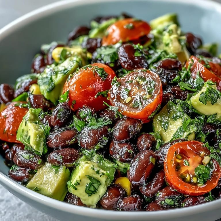 Colorful ingredients for a Black Bean and Veggie Bowl mixed in a bowl: black beans, sweet corn, red onion, and tomatoes.