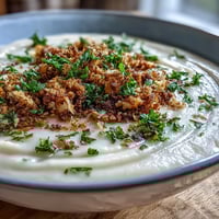 Velvety celeriac soup with crunchy hazelnut crumble topping, a perfect autumn comfort.
