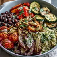 A colorful Veggie and Quinoa Power Bowl with roasted vegetables, beans, and a lemon dressing, served in a ceramic bowl.