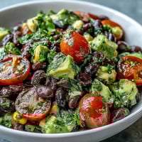 Close-up of the Black Bean and Veggie Bowl with diced avocado, halved cherry tomatoes, and fresh cilantro, drizzled with zesty lime dressing.