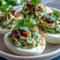 Creamy guacamole stuffed deviled eggs with avocado, lime, and a hint of jalapeño for a fresh, flavorful appetizer.