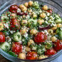 A vibrant cold chickpea salad with lemon herbs, fresh cucumbers, and juicy tomatoes, perfect for summer meals.  